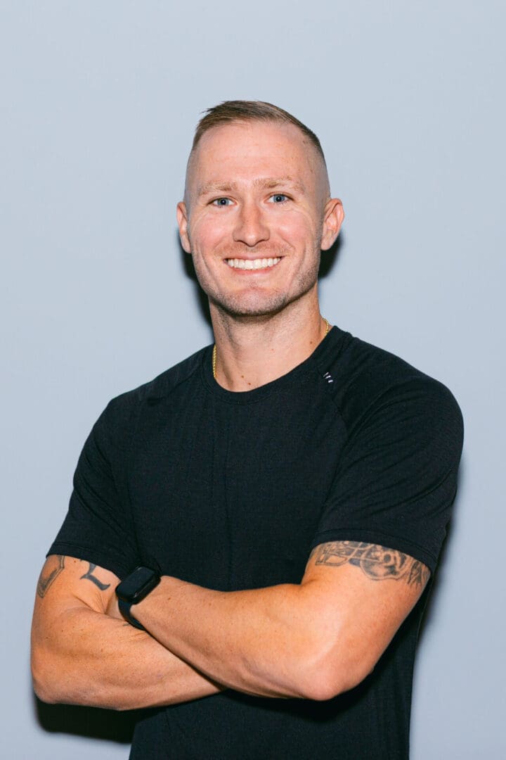 Smiling man with arms crossed, wearing black shirt.